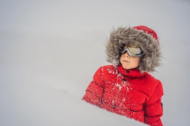 Happy boy playing in the snow with ski goggles