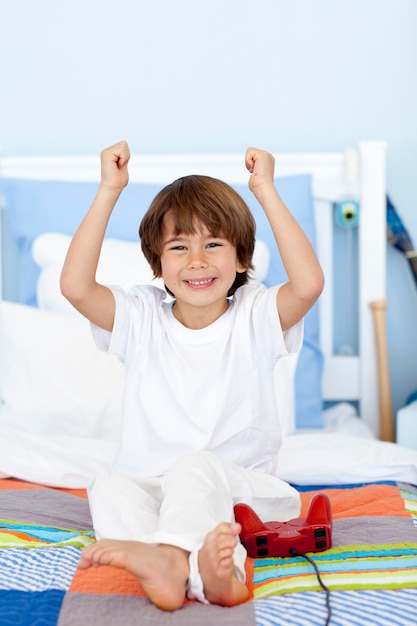 Happy boy playing videogames in bedroom