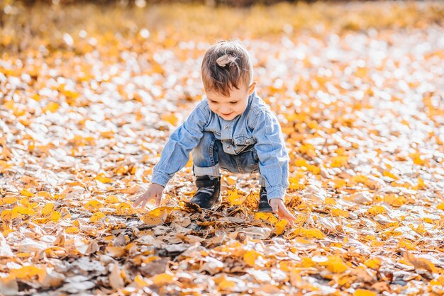 Happy boy playing with autumn yellow leaves outdoors in the Park