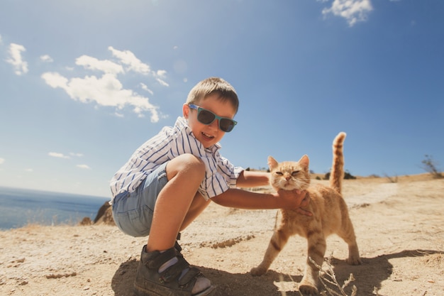 Happy boy playing with red cat