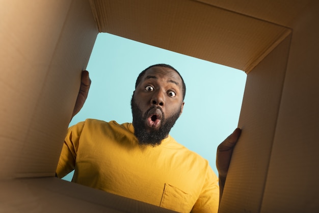 Happy boy receives a package from online shop order. happy and surprised expression. Blue wall.