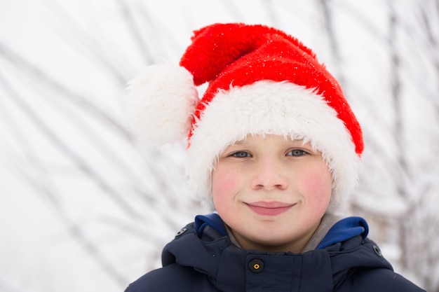 Happy boy in santa hat on the street in winter