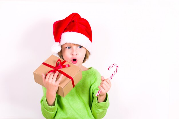 Happy boy in Santa red hat holding Christmas gift in hand. Christmas concept.