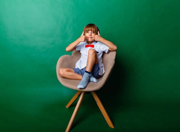 Happy boy sits on a chair and shows the class. Educational and school concept