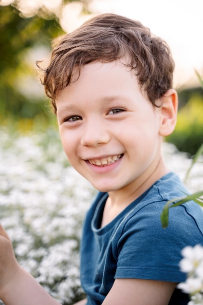 Foto ragazzo felice che sorride tra i fiori bianchi