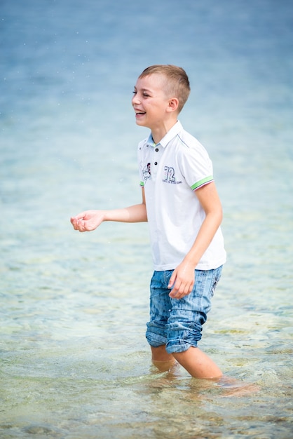 Happy boy standing in front of the sea in summertime