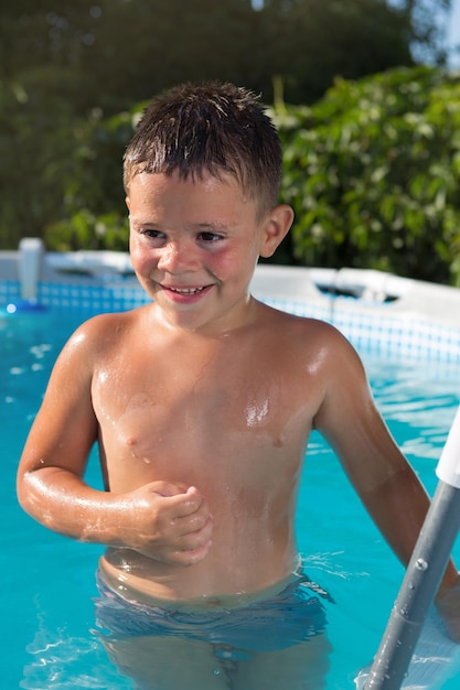 사진 행복한 소년은 수영장에 서서 여름 방학을 웃습니다.