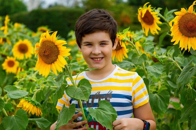 Foto un ragazzo felice in piedi tra i fiori di girasole in estate nel parco