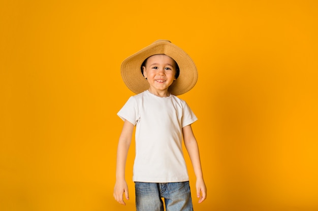 Счастливый мальчик в соломенной шляпе на желтой поверхности с пространством для текста