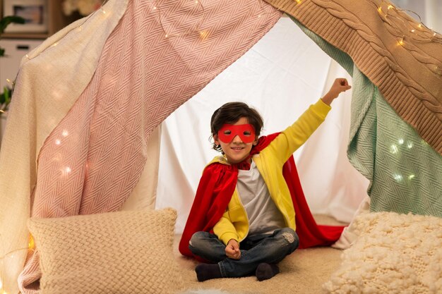 happy boy in super hero stuff in kids tent at home