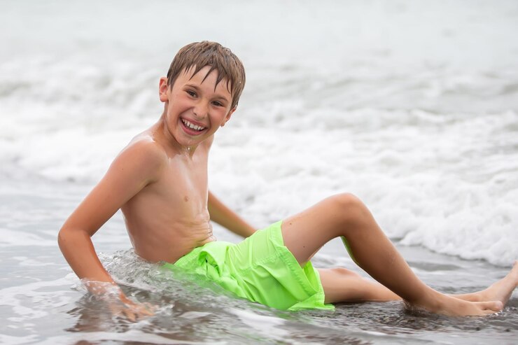 Happy boy swims at the sea looks into the camera Summer rest