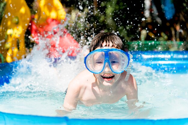 Ragazzo felice in una maschera subacquea nuotare in piscina