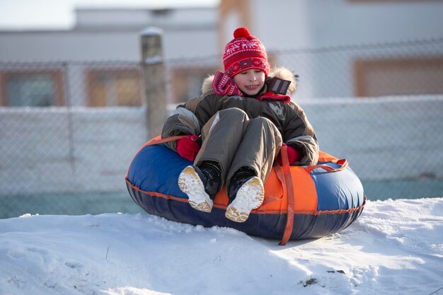 A happy boy up in the air on a tube sledding in the snow a boy\
slides down a hill in winter