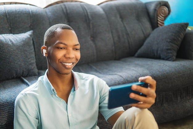 Happy boy watching and listening to video on phone sitting on a sofa at home