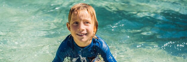 Photo happy boy on water slide in a swimming pool having fun during summer vacation in a beautiful