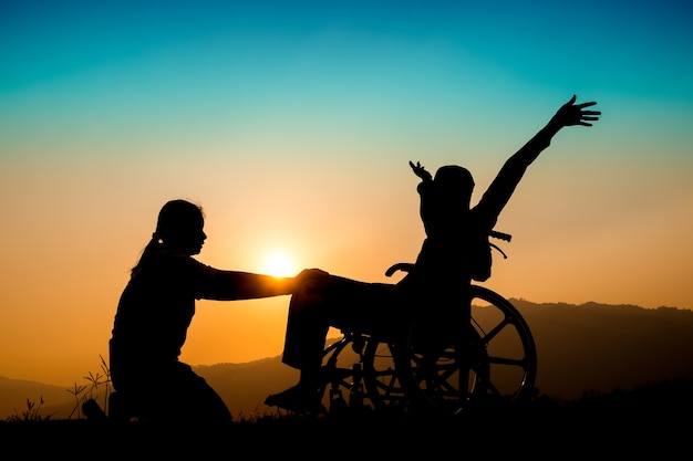 Photo happy boy in wheelchair and sister on sunset. happy disabled child concept