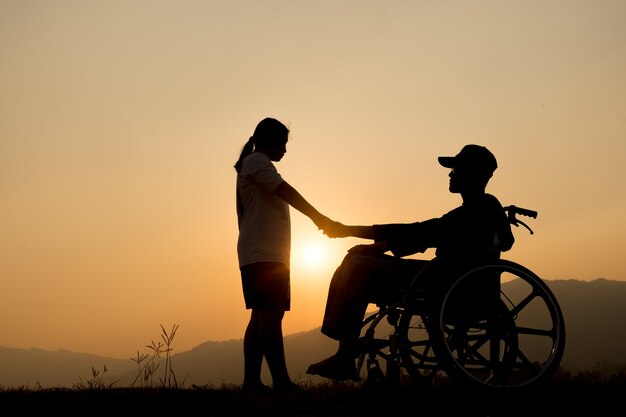 Happy boy in wheelchair and sister on sunset. Happy disabled child concept