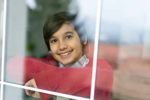 Happy boy behind window glass