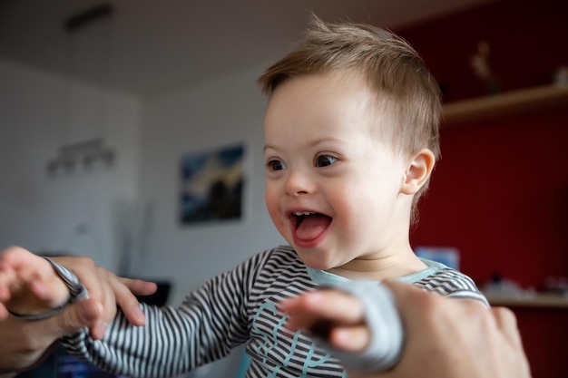 happy boy with down syndrome held by father at home