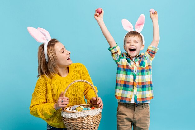 Happy boy with mom holding basket with painted eggs