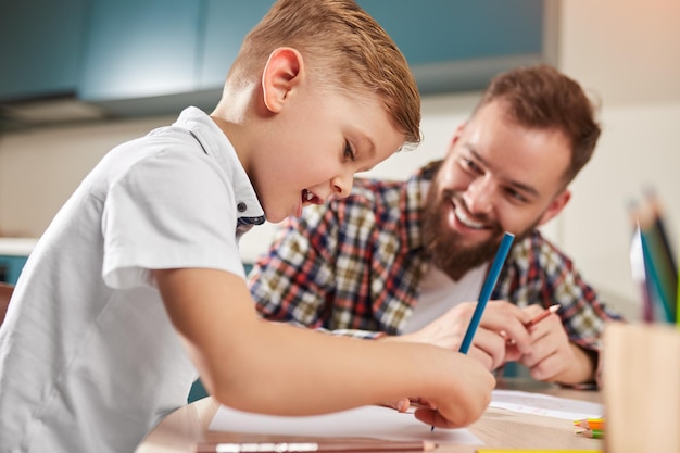 Happy boy with young father doing homework together