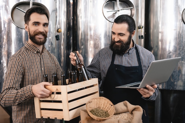 Happy Brewers die bierflessen inspecteren in de fabriek.