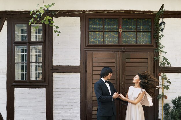 Happy bride and bridegroom standing close to each other at old house background, wedding photo, beautiful couple, wedding day, portrait.