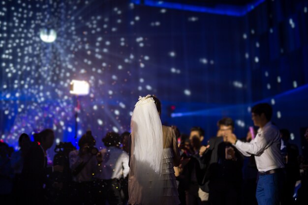 Happy bride first dance at wedding party with guests and colour led lighting.