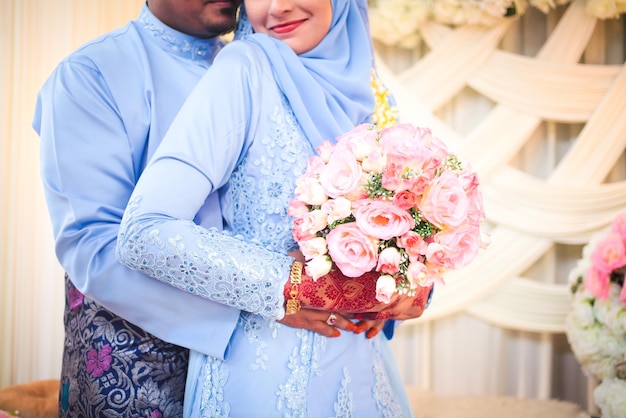 幸せな花嫁と花婿は彼らの結婚式でお互いに手をつないでいますマレーの結婚式アジアの結婚式