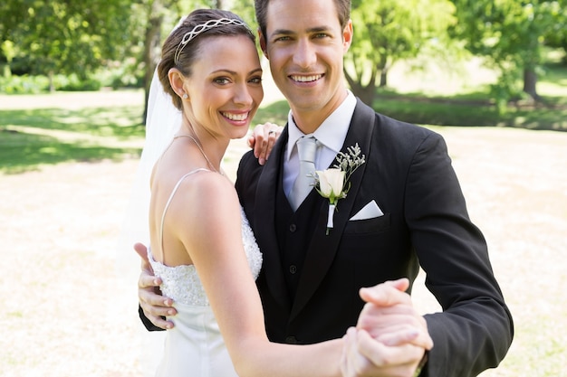 Happy bride and groom dancing together in garden