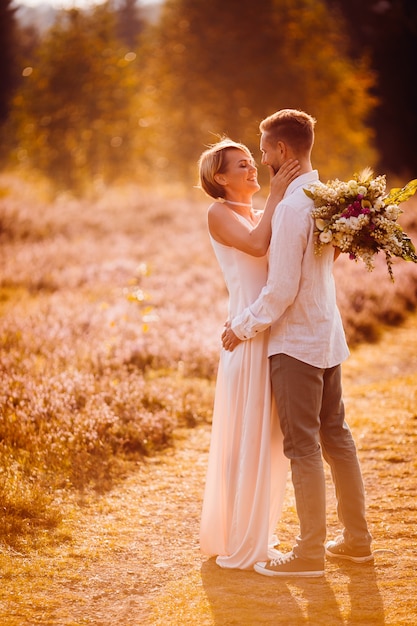 Happy bride and groom pose on the violet field 