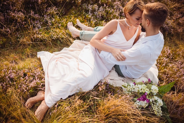 Happy bride and groom pose on the violet field 