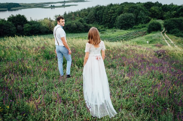 Happy Bride and groom walking on the green grass