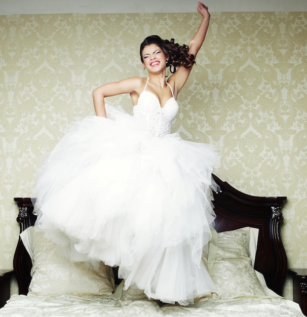 Photo happy bride jump on bed