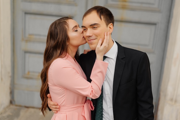 La sposa felice bacia lo sposo sulla guancia vicino alla porta della chiesa.