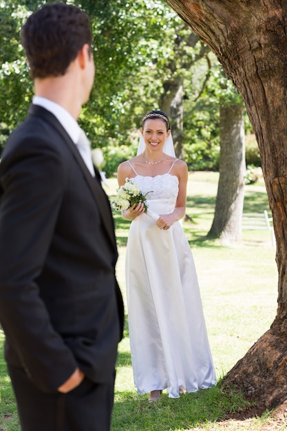 Happy bride looking at groom in garden