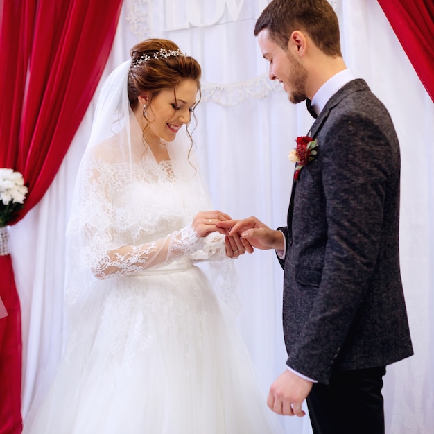 Happy bride wears a wedding ring for her husband in the presence