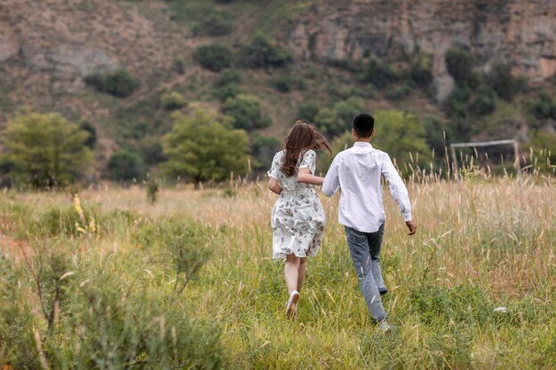 Happy bride in wedding dress and groom holding hands and walking