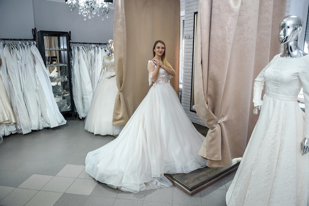 Happy bride in wedding dress standing in salon