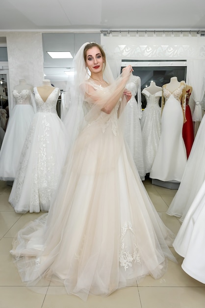 Happy bride in wedding dress standing in salon