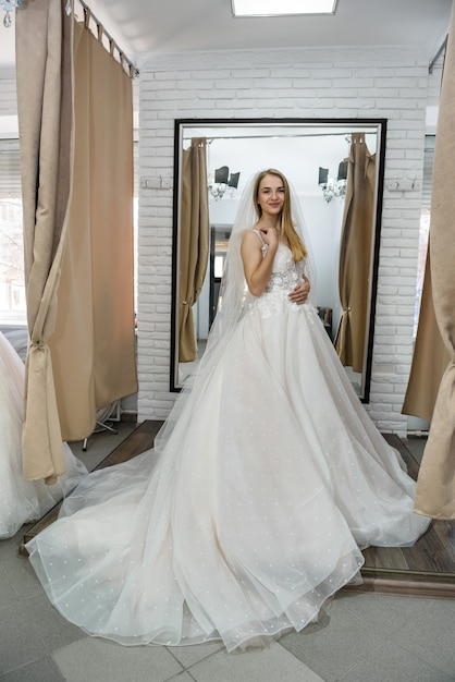 Happy bride in wedding dress standing in salon