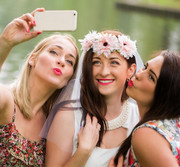 Photo happy bride with friends taking selfie