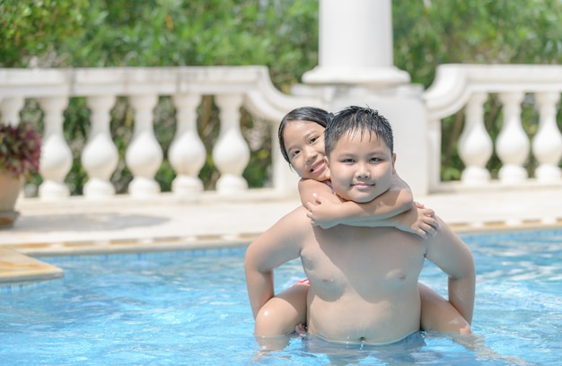 Happy brother and sister play in swimming pool, 