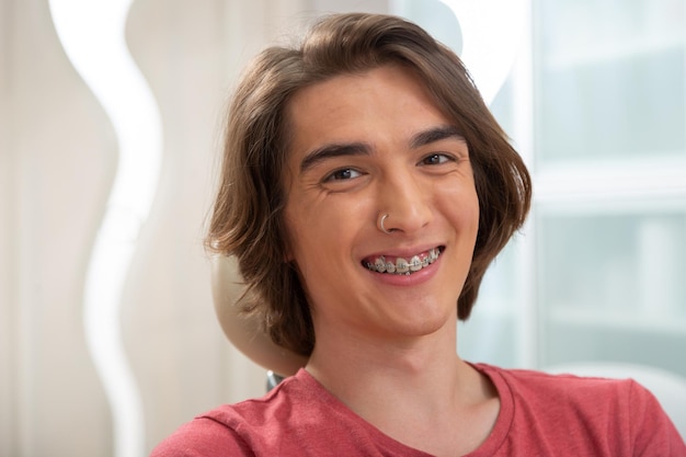 Photo happy browneyed young man in dental clinic