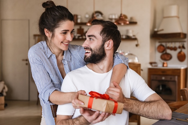 Felice coppia bruna uomo e donna facendo colazione in appartamento mentre era seduto al tavolo con la presente casella