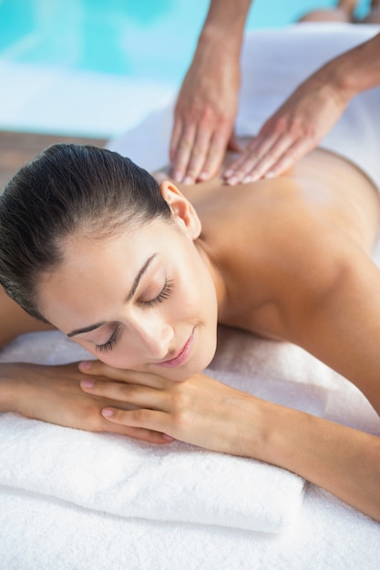 Happy brunette enjoying a massage poolside