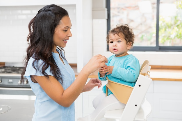 Happy brunette feeding her baby in the kitchen