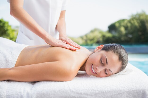 Happy brunette getting a massage poolside