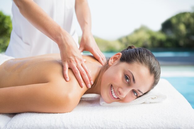 Happy brunette getting a massage poolside