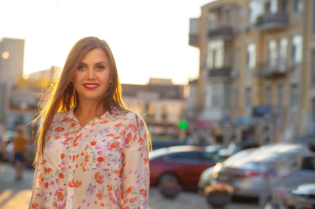 Happy brunette model wearing blouse and pink jacket posing at the evening city background. Space for text